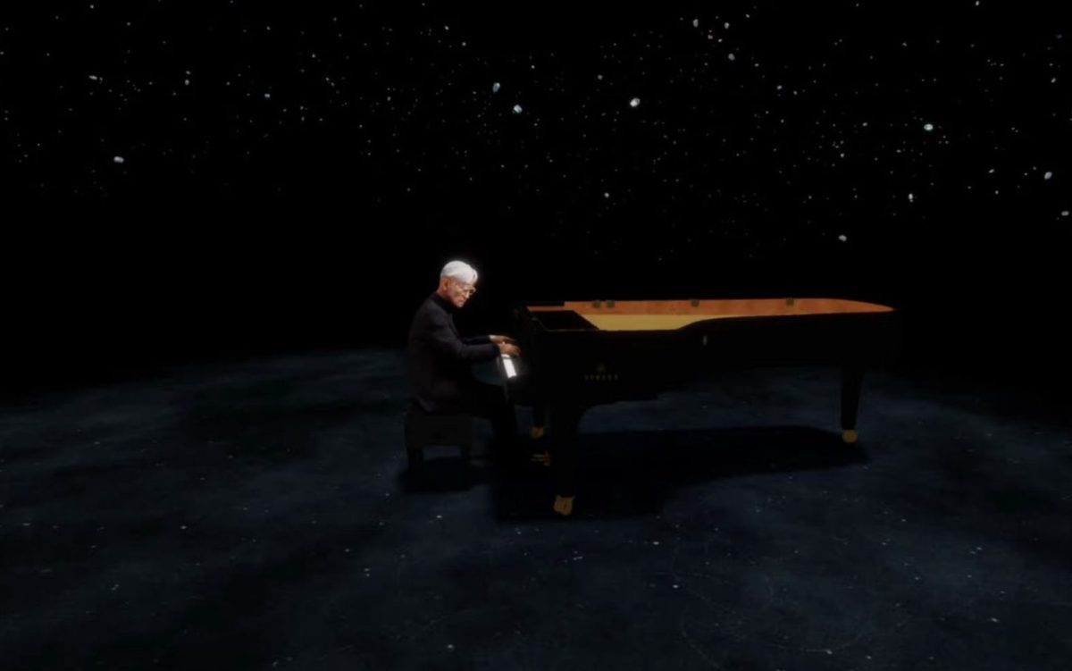 Ryuichi Sakamoto in mixed-reality, ‘KAGAMI’. A virtual image of Sakamoto playing a black grand piano in a limbo or dark virtual space.