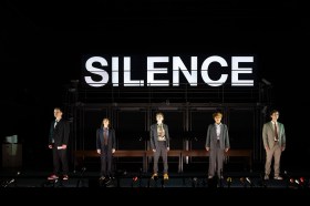 Five people wearing suits stand across a dark stage, with the large word SILENCE above their heads. Truth at Malthouse.