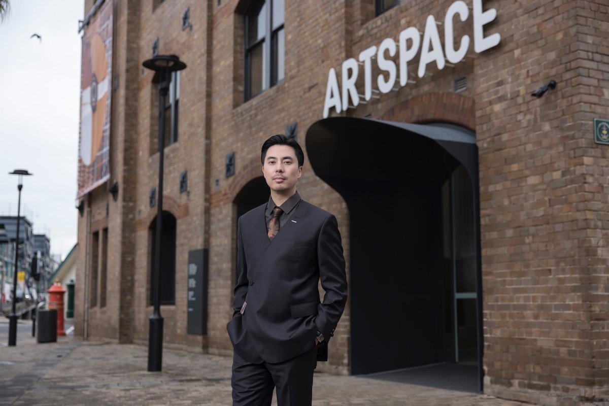 Asian man in dark suit standing in front of building in formal pose. Victor Wang. Artspace.