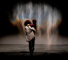 Woman holding a child in front of an art installation using mist. Olafur Eliasson