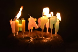 Birthday cake with glowing candles in blackened room. Arts anniversaries