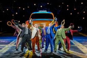 Group of men in colourful suits singing on stage. Guys & Dolls