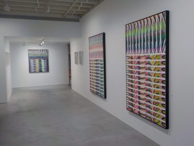 A gallery space showing paintings full of colour and patterns by Karl Shoobridge.