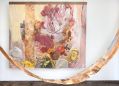 Emily Imeson, ‘Floating QLD Waratah turned Flame Tree Season,’ 2021 (detail), recycled timber, acrylic on canvas, thread, batik earth-stained cotton, 210 x 240cm. Courtesy of the artist. A photo of a forest-themed artwork, including a curved piece of wood which helps frame the image.