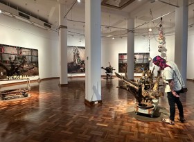 Gallery view of an exhibition with sculptures and male visitor. Karla Dickens