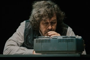 Irish actor Stephen Rea in Samuel Beckett's 'Krapp's Last Tape' at Adelaide Festival 2025. The photograph depicts Rea, an older fair-skinned man with an unruly shock of greying hair, hunched over an old reel-to-reel tape deck to which he listens anxiously.