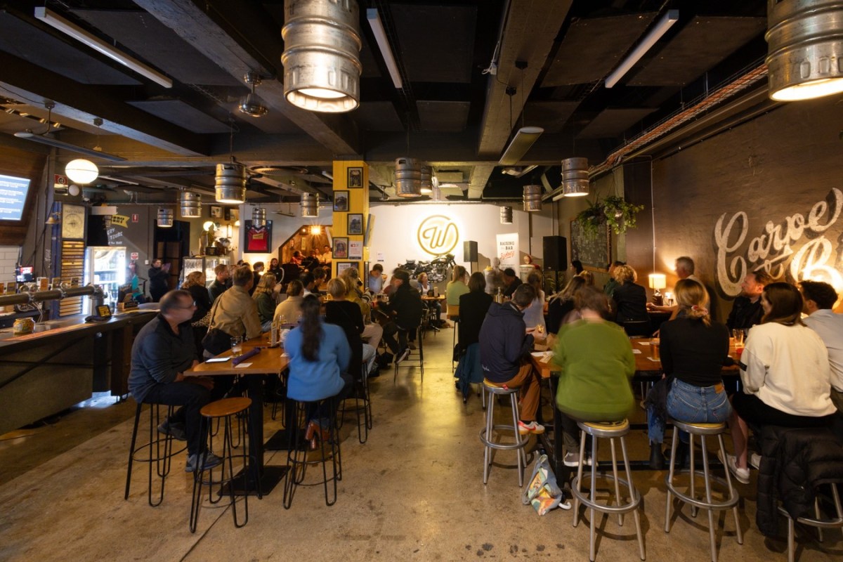 A bar full of people sitting on stools. 