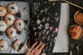 A hand on the open pages of a cookbook