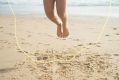 ArtsHub's sweekly On the Move column is an overview of Australian arts sector comings and goings. The photo depicts a person skipping rope at the beach, with the focus being their bare feet as they skip, the sand and the skipping rope itself.